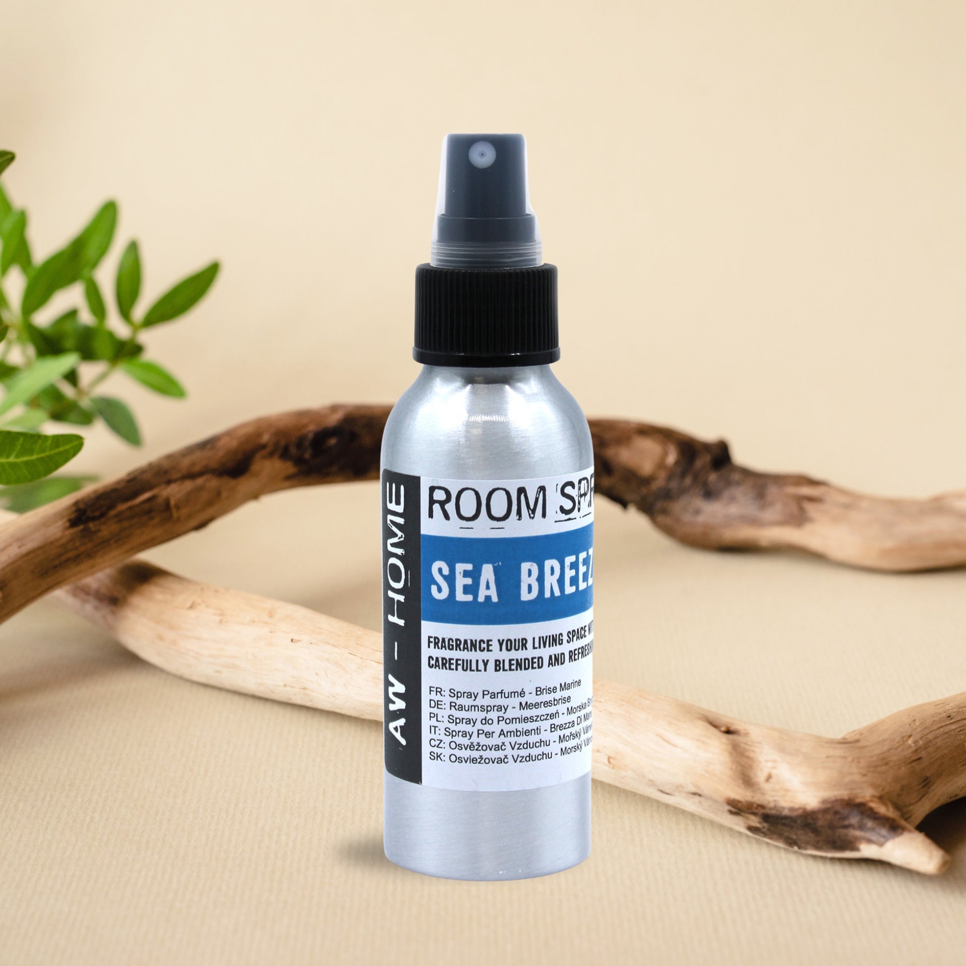 Spray ambiental Sea Breeze de 100 ml en un frasco de aluminio sobre una mesa decorada con ramas naturales.