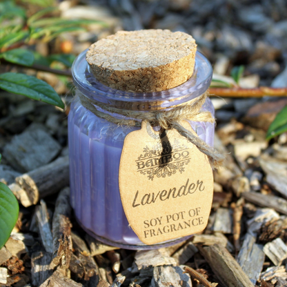 Vela de cera natural con fragancia a lavanda en un entorno de bosque, rodeada de virutas de madera y plantas, transmitiendo calma y conexión con la naturaleza.